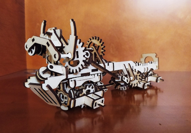 May include: A wooden model of a complex machine with gears, levers, and other moving parts. The model is made of natural wood and has a rustic, steampunk aesthetic.