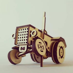 以下が含まれることがあります： 茶色と白の色の木製のおもちゃのトラクター。トラクターは、グリル、車輪、ステアリングホイールを備えた詳細なデザインです。
