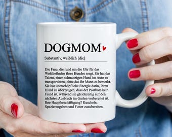 Puede incluir: Taza de café de cerámica blanca con un diseño en blanco y negro que dice "DOGMOM" y una definición de la palabra. La definición está en alemán.
