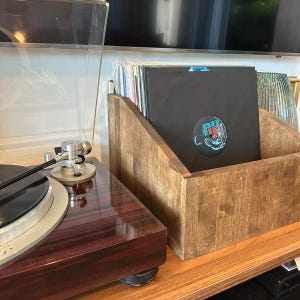 May include: A wooden record storage box with a dark brown stain. The box is filled with vinyl records, including one with a black and blue cover featuring the text "The Black Keys".
