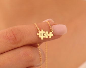 May include: Gold necklace with a puzzle piece pendant featuring the initials "ECS".