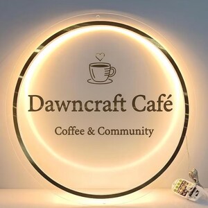May include: Circular cafe sign with a warm, glowing light. The sign features the text "Dawncraft Caf&eacute;" in a serif font, along with the words "Coffee & Community" below. A coffee cup icon with a heart above it is also present.