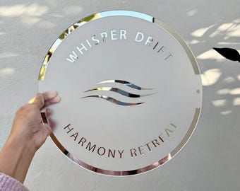 May include: A round, silver-edged sign with the words "Whisper Drift" and "Harmony Retreat" in a sans-serif font. The sign features a stylized wave design in the center. The sign is held by a person.