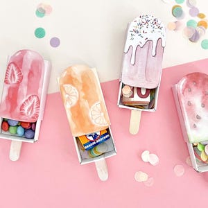 Könnte beinhalten: Vier Eis am Stiel-förmige Geschenkboxen aus Papier mit Schiebefächern, mit Erdbeer-, Orangen-, Vanille-mit-Streuseln- und Wassermelonen-Designs. Die Boxen enthalten kleine Süßigkeiten und Geld. Text: DIY MINI-BANDEROLE EIS AM STIEL 4 DESIGNS PDF SOFORT DOWNLOAD PRINT A4.