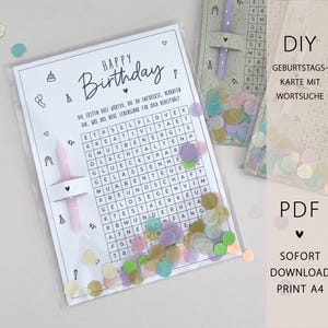 May include: A birthday card with a word search puzzle, the words are in German. The card is in a clear plastic sleeve with confetti and a pink candle. The words "Happy Birthday" are at the top.
