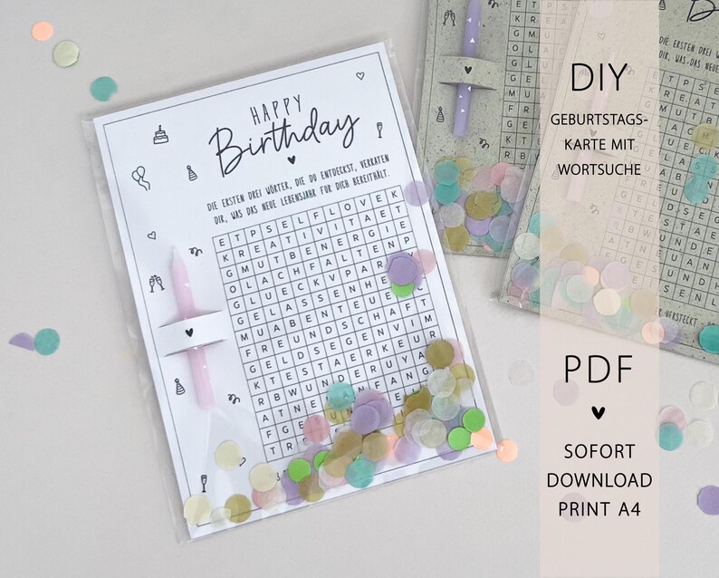May include: A birthday card with a word search puzzle, the words are in German. The card is in a clear plastic sleeve with confetti and a pink candle. The words "Happy Birthday" are at the top.