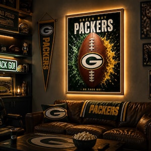 May include: A wall-mounted, backlit rectangular poster featuring a brown football with the Green Bay Packers logo, surrounded by green and yellow paint splashes. The text reads GREEN BAY PACKERS and GO PACK GO in white lettering.