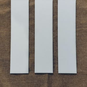 May include: Three white rectangular pieces of paper on a brown textured surface.
