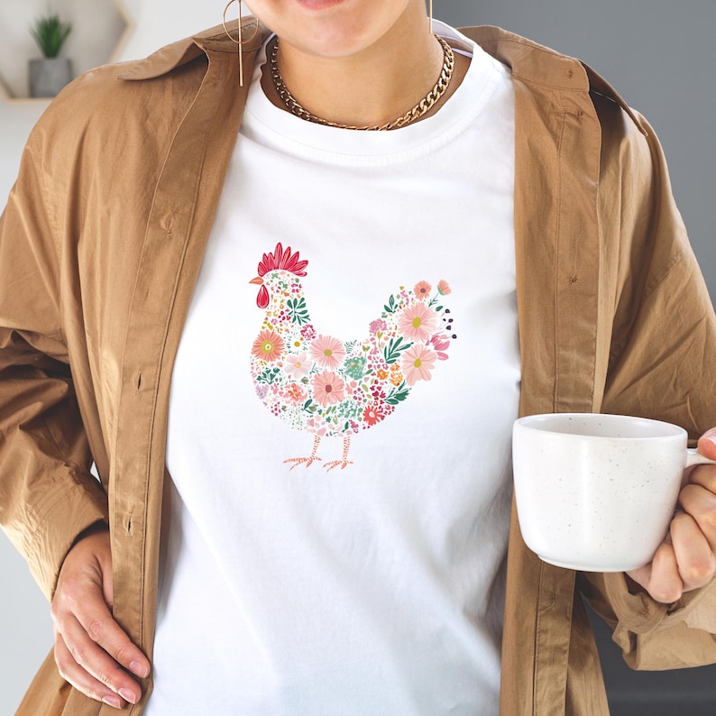May include: White t-shirt featuring a floral hen design. The hen is composed of pink, red, and green flowers. The shirt is a classic crew neck style.