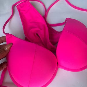 Puede incluir: Un top de bikini de color rosa brillante con tirantes ajustables. El top tiene un estilo push-up y está hecho de una tela suave y elástica.