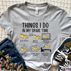 May include: A heather grey t-shirt featuring the text THINGS I DO IN MY SPARE TIME and six illustrations of yellow geckos with captions: FEED GECKOS, WATCH GECKOS, RESEARCH GECKOS, TALK ABOUT GECKOS, THINK ABOUT GECKOS, and DREAM ABOUT GECKOS.
