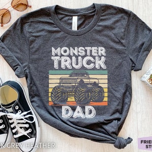 May include: Dark grey heather t-shirt with a vintage-style graphic of a monster truck and the text "Monster Truck Dad".