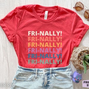 May include: Heather red t-shirt with the text "FRI-NALLY!" repeated six times in rainbow colors. The shirt is shown on a model wearing blue jeans.