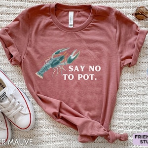 May include: Heather mauve t-shirt featuring a crawfish graphic and the text "Say No To Pot."