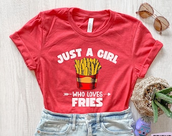 Może przedstawiać: Czerwona koszulka z białym napisem "Just a girl who loves fries" i grafiką czerwonego i żółtego pojemnika na frytki.