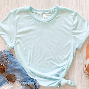 May include: A light blue t-shirt with a crew neck and short sleeves. The shirt is made of a soft, comfortable fabric and is perfect for everyday wear.