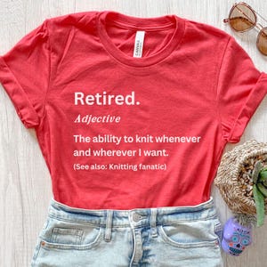 Puede incluir: Una camiseta roja con la palabra "Retired" impresa en blanco, junto con una definici&oacute;n sobre tejer. La camiseta se combina con pantalones cortos de mezclilla y gafas de sol, lo que sugiere un estilo casual y relajado.