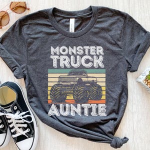 May include: Gray t-shirt with a vintage-style graphic of a monster truck and the text "Monster Truck Auntie".