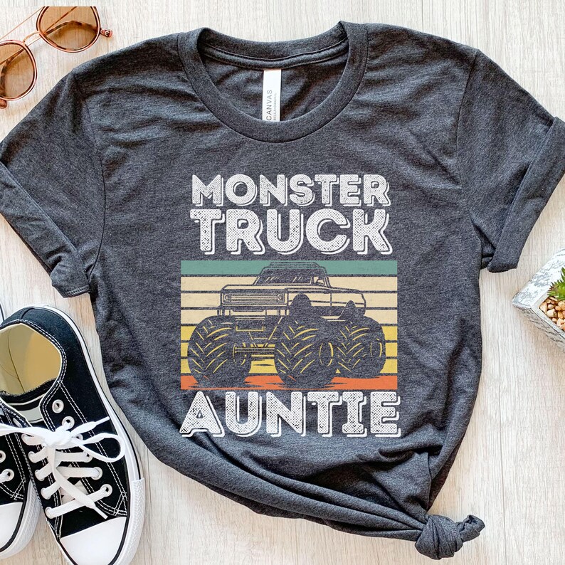 May include: Gray t-shirt with a vintage-style graphic of a monster truck and the text "Monster Truck Auntie".