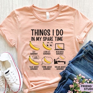 Peut inclure: Un t-shirt couleur p&ecirc;che avec le texte "Things I do in my spare time" et une s&eacute;rie d'illustrations de bananes avec du texte sur le fait de manger, de regarder, de rechercher, de parler, de penser et de r&ecirc;ver de bananes.