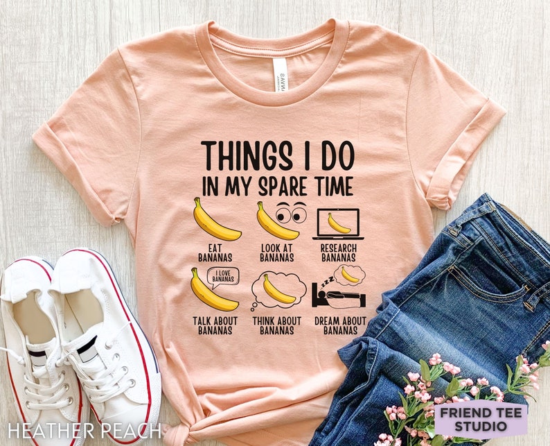 Peut inclure: Un t-shirt couleur p&ecirc;che avec le texte "Things I do in my spare time" et une s&eacute;rie d'illustrations de bananes avec du texte sur le fait de manger, de regarder, de rechercher, de parler, de penser et de r&ecirc;ver de bananes.