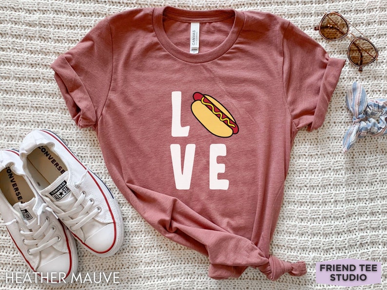 May include: A heather mauve t-shirt with a white graphic of a hot dog and the word "LOVE".
