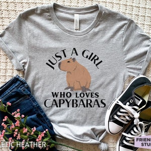 May include: A gray t-shirt with the text "Just a girl who loves capybaras" and a cartoon image of a capybara.