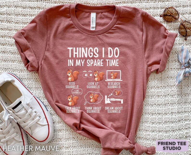 May include: Heather mauve t-shirt with a white graphic that says "Things I do in my spare time" and features illustrations of squirrels. The illustrations show squirrels being fed, looked at, researched, talked about, thought about, and dreamed about.