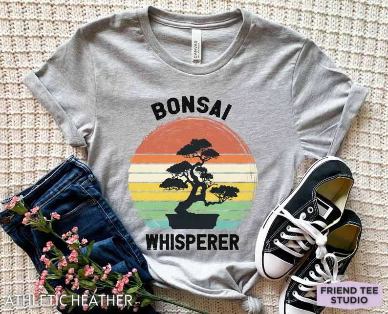 May include: A gray t-shirt with a vintage-style graphic of a bonsai tree and the text "Bonsai Whisperer".