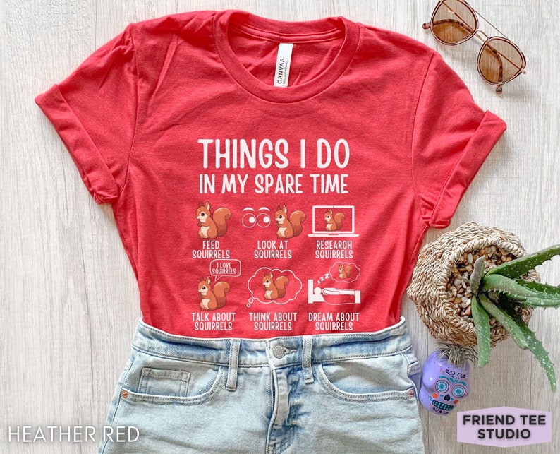 May include: Red t-shirt with the text "Things I do in my spare time" and illustrations of squirrels. The text below the squirrels includes phrases like "Feed squirrels", "Look at squirrels", "Research squirrels", "Talk about squirrels", "Think about squirrels", and "Dream about squirrels".
