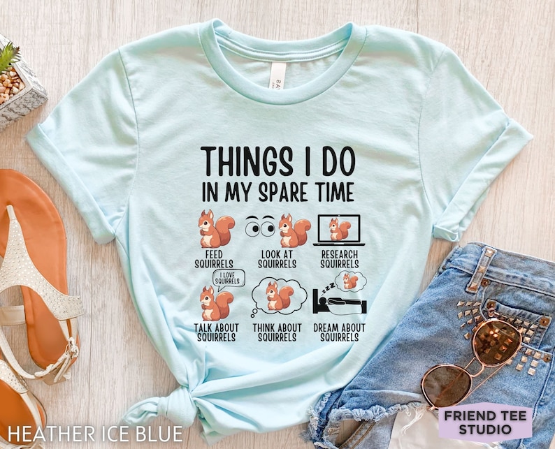 May include: A light blue t-shirt with the text "Things I do in my spare time" and a series of illustrations of squirrels. The illustrations depict squirrels feeding, looking at, researching, talking about, thinking about, and dreaming about squirrels.