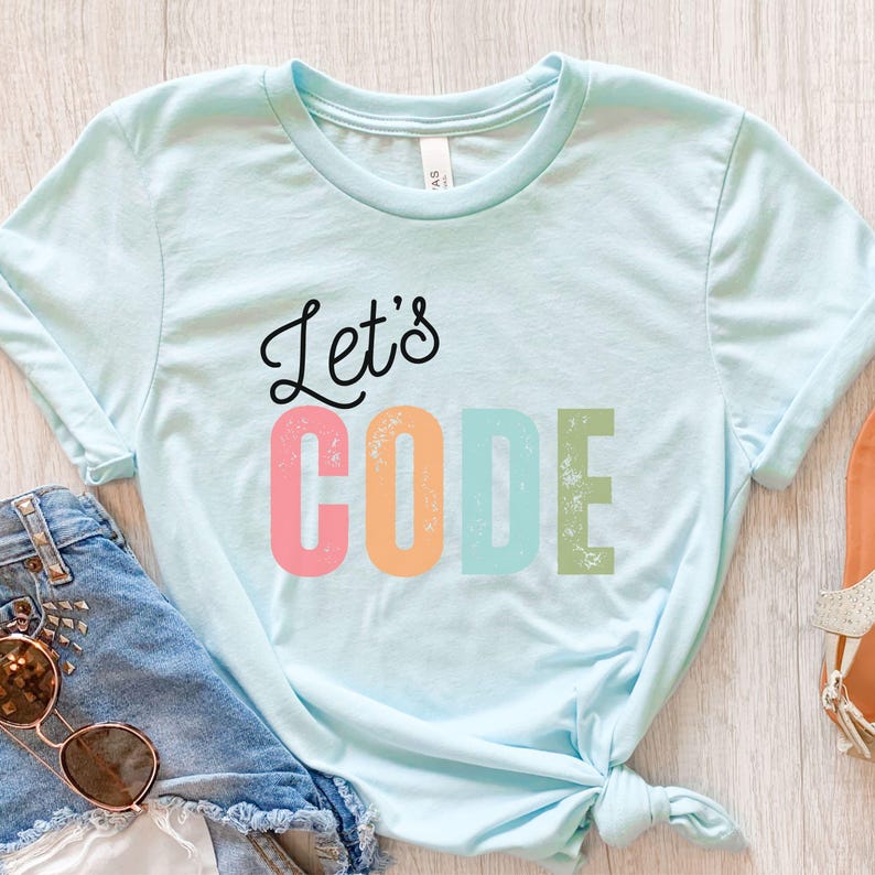 K&ouml;nnte beinhalten: Hellblaues T-Shirt mit dem Schriftzug "Let's CODE" in einer bunten, verwitterten Schriftart. Das Shirt ist am unteren Ende geknotet und wird mit Jeansshorts und Sonnenbrille gezeigt.