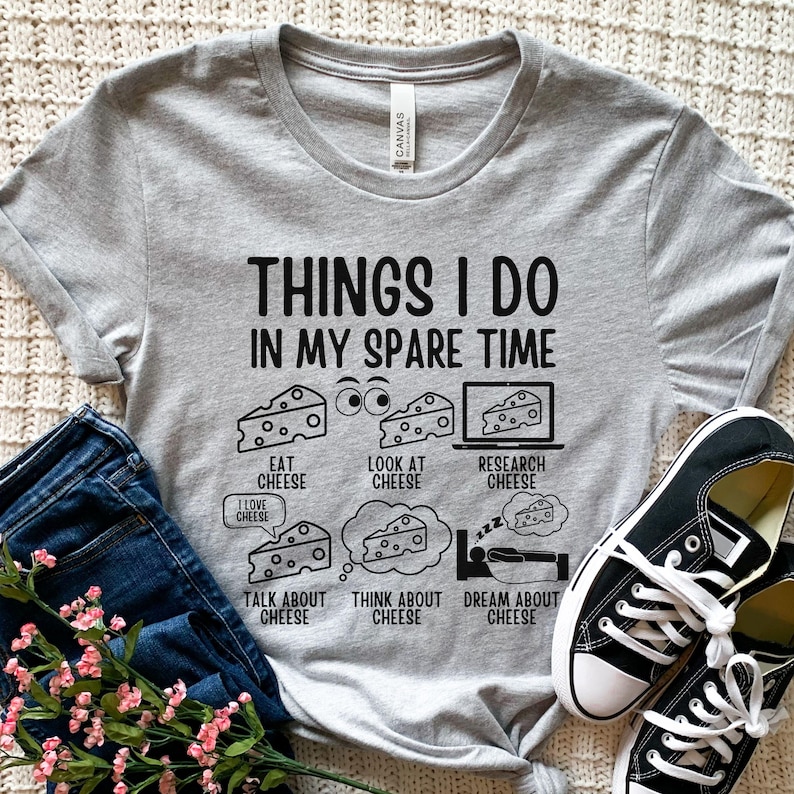 Puede incluir: Una camiseta gris con el texto "Things I do in my spare time" y una lista de actividades relacionadas con el queso: comer queso, mirar queso, investigar queso, hablar de queso, pensar en queso y so&ntilde;ar con queso.