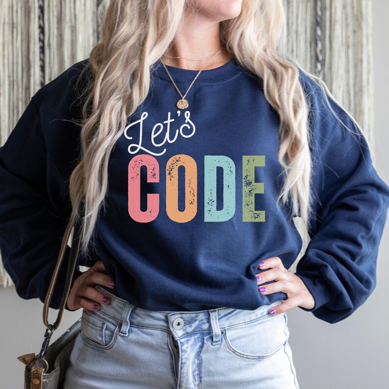 K&ouml;nnte beinhalten: Marineblaues Sweatshirt mit dem Text "Let's CODE" in wei&szlig;er Schrift und bunten Blockbuchstaben. Das Sweatshirt ist ein l&auml;ssiges Kleidungsst&uuml;ck f&uuml;r den Alltag.