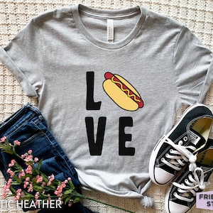 May include: A gray t-shirt with the word "LOVE" printed on it. The "O" in LOVE is replaced with a cartoon hot dog.