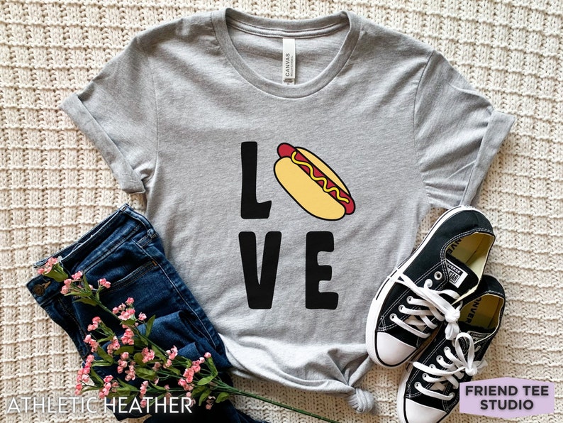May include: A gray t-shirt with the word "LOVE" printed on it. The "O" in LOVE is replaced with a cartoon hot dog.