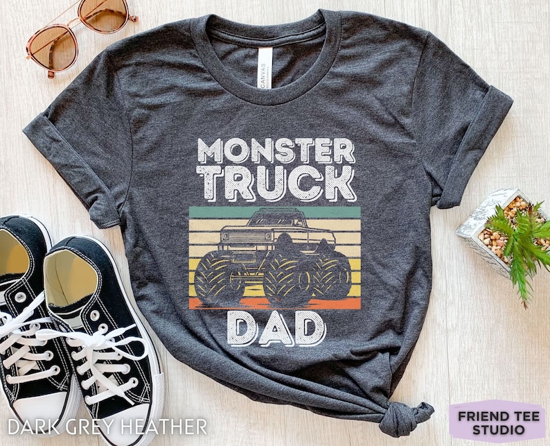 May include: Dark grey heather t-shirt with a vintage-style graphic of a monster truck and the text "Monster Truck Dad".