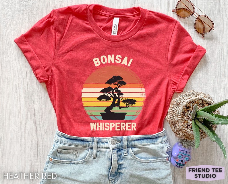 May include: Red t-shirt with a vintage-style graphic of a bonsai tree and the text "Bonsai Whisperer".