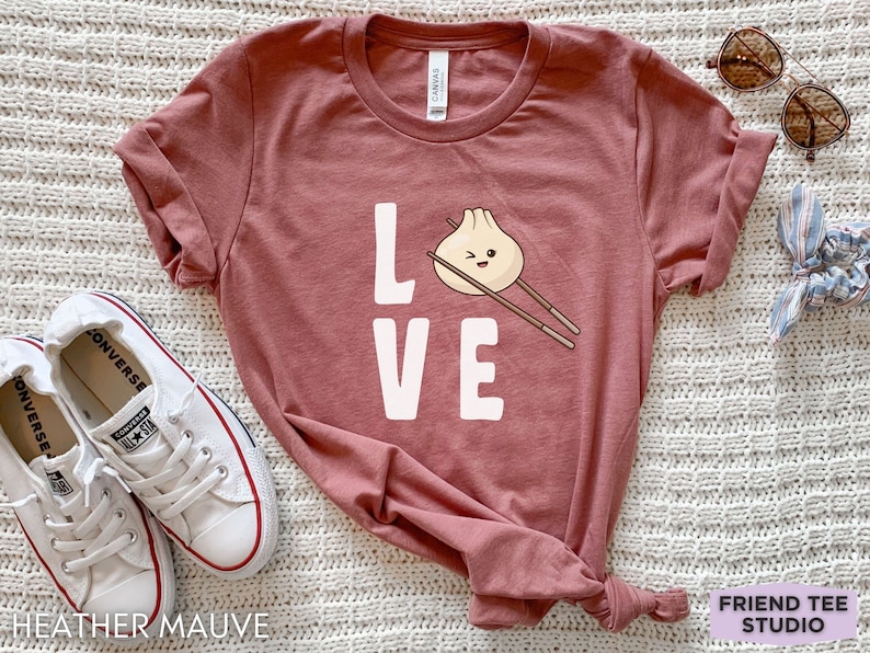 Op de afbeelding: Heather mauve t-shirt met het woord "LOVE" in wit gedrukt. De "O" is vervangen door een cartoon-dumpling met eetstokjes.