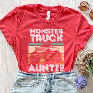 May include: Red t-shirt with a vintage-style graphic of a monster truck and the text "Monster Truck Auntie".