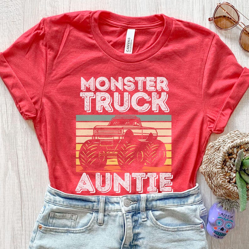 May include: Red t-shirt with a vintage-style graphic of a monster truck and the text "Monster Truck Auntie".