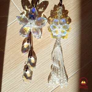 May include: Two crystal flower car charms with iridescent rainbow colours. One charm has a flower with a tassel and the other has a flower with three crystal drops.