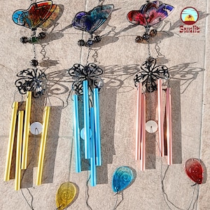 Peut inclure: Trois carillons éoliens avec des motifs de papillons et de fleurs. Les carillons présentent des dessus de papillons colorés, des éléments en métal noir et des couleurs de carillons variables, dont l'or, le bleu et le rose. Chaque carillon a un accent en verre décoratif en bas.