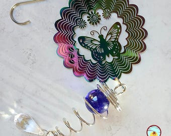 May include: A rainbow iridescent metal wind spinner with a butterfly design and a blue glass bead hanging from a silver spring.