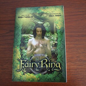 Pode incluir: Uma capa de livro com fundo verde, amarelo e marrom. O título é "Guide to the Fairy Ring" com uma ilustração verde e amarela de um círculo de fadas. O livro foi escrito por Anna Franklin e ilustrado por Paul Mason.