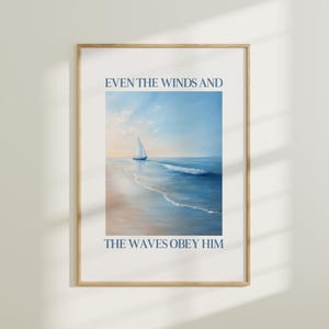 May include: A framed art print depicting a tranquil seascape with a sailboat. The image uses blue and beige tones, and includes the navy text: "EVEN THE WINDS AND THE WAVES OBEY HIM". The frame is a light brown colour.