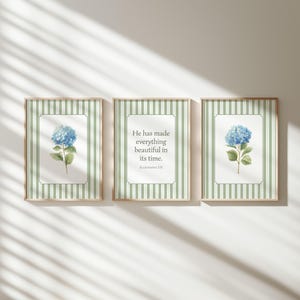 May include: Three framed prints with a watercolor illustration of a blue hydrangea flower. The frames have a green and white striped background. The center print has the text "He has made everything beautiful in its time."