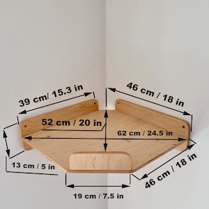 May include: A wooden corner shelf with measurements in inches and centimeters. The shelf is made of light wood and has a simple design. It is 20 inches wide, 18 inches deep, and 24.5 inches long.