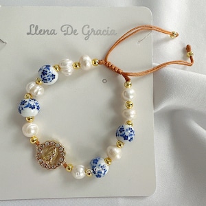 Preciosa pulsera con colgante de la Virgen de Guadalupe en oro de 14 quilates, elaborada con perlas naturales de agua dulce y cuentas de acero quirúrgico. Incluye caja