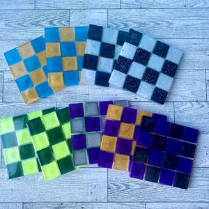 May include: Set of ten colorful ceramic coasters with a checkered pattern. The coasters are in shades of blue, green, yellow, black, and purple.
